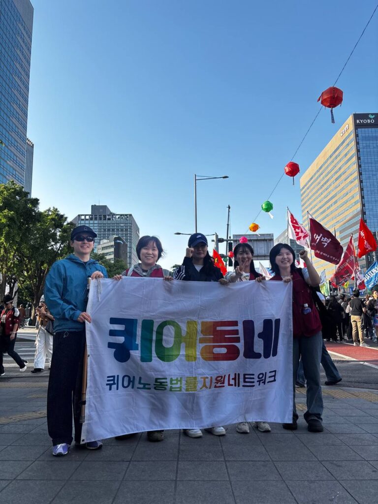 퀴어동네 회원들이 노동절 집회 현장에서 깃발을 들고 포즈를 취하고 있다